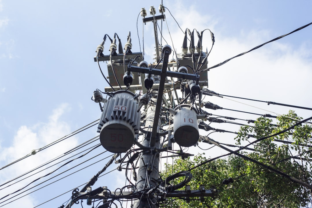 gray electric post under blue sky during daytime