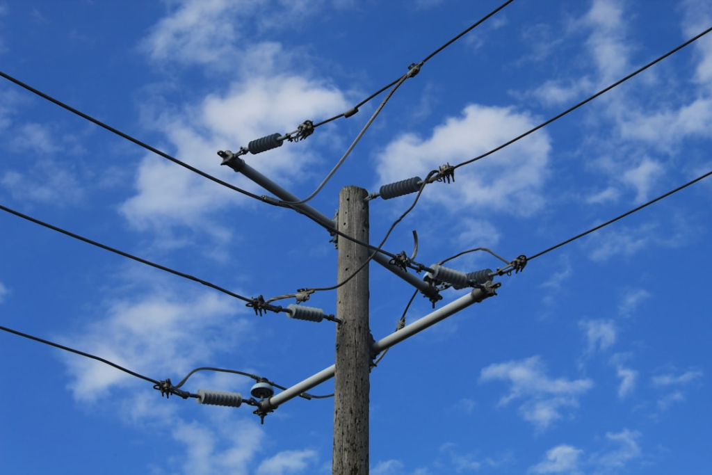 brown wooden electric post under blue sky during daytime