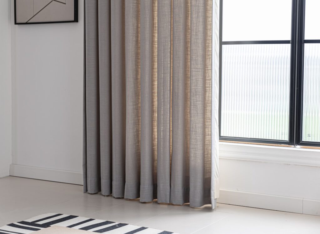 Curtains frame a window in a bright room.