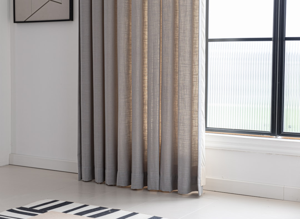 Curtains frame a window in a bright room.